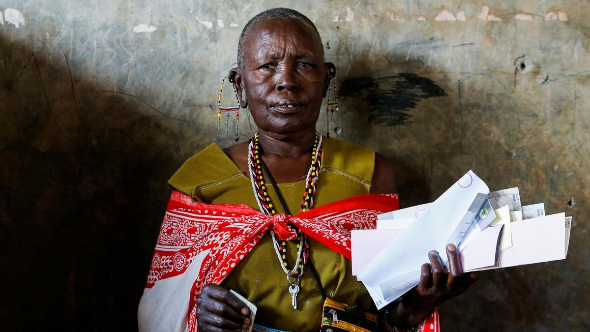 Una mujer tradicional masai espera en un centro de votación antes de emitir su voto durante las elecciones generales en el condado de Kajiado, Kenia 