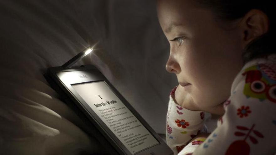 Una niña lee un cuento (en inglés) en un soporte electrónico.