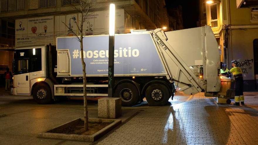 Un camión del servicio de recogida de residuos vacía contenedores en una calle de la ciudad.