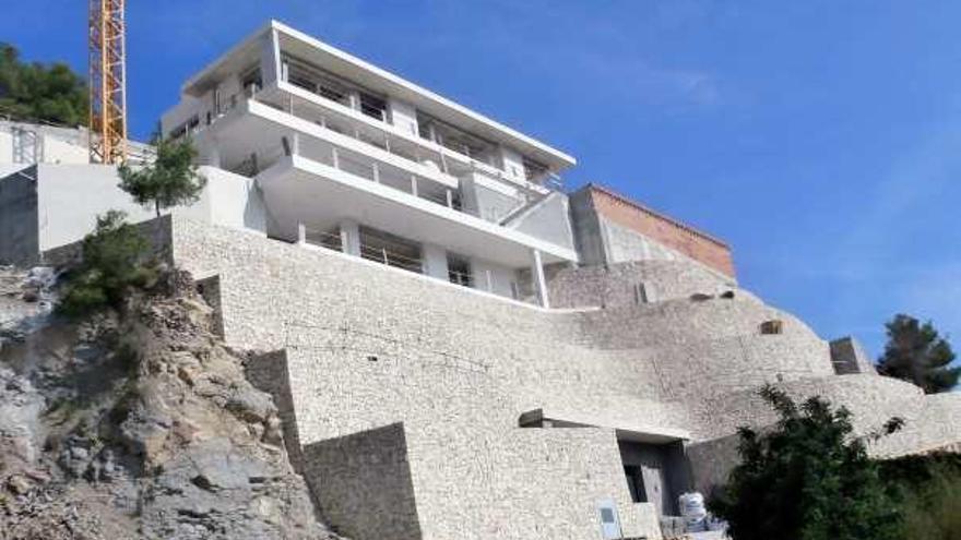 Chalé en construcción en la playa de la Barraca sostenido en un imponente muro de piedra.