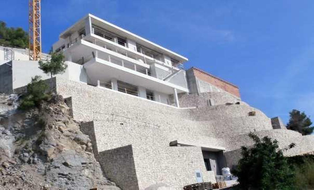 Chalé en construcción en la playa de la Barraca sostenido en un imponente muro de piedra.