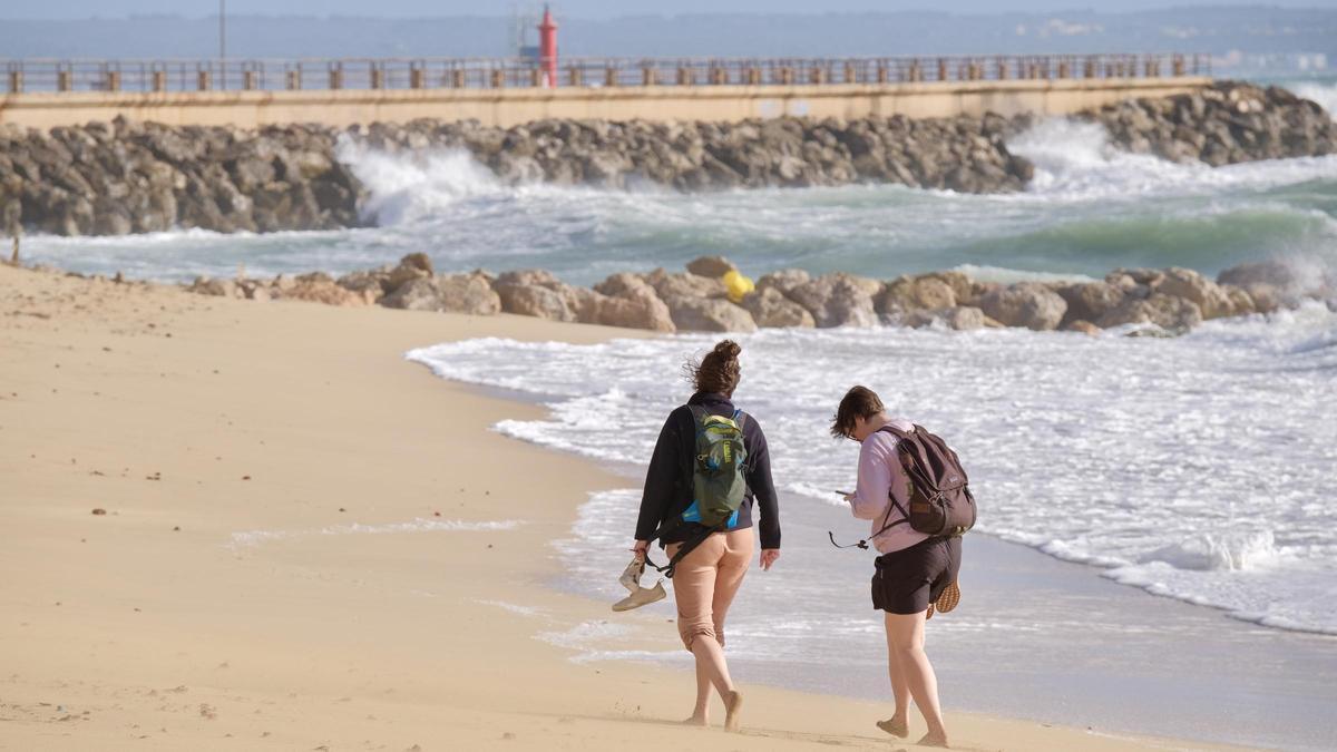 Dos jóvenes pasean por la playa de Can Pere Antoni, en Palma