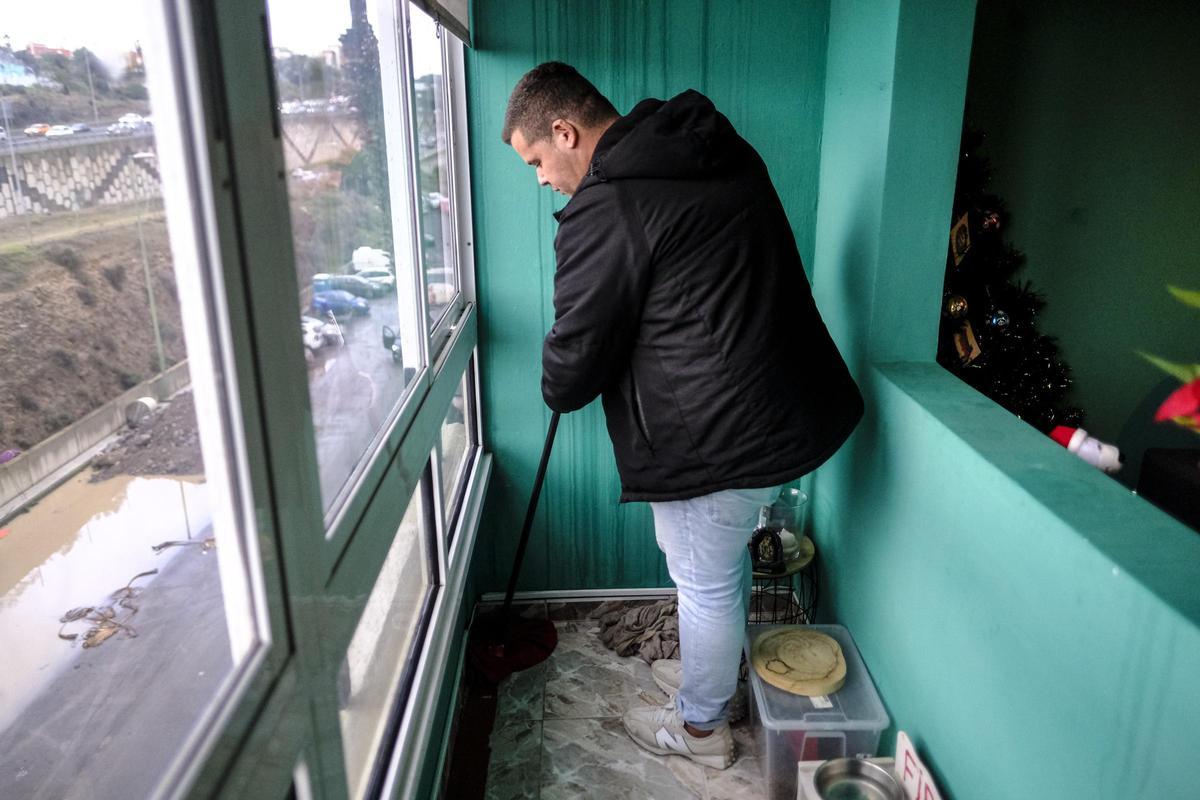 Un vecino seca el agua que se ha filtrado a su vivienda.