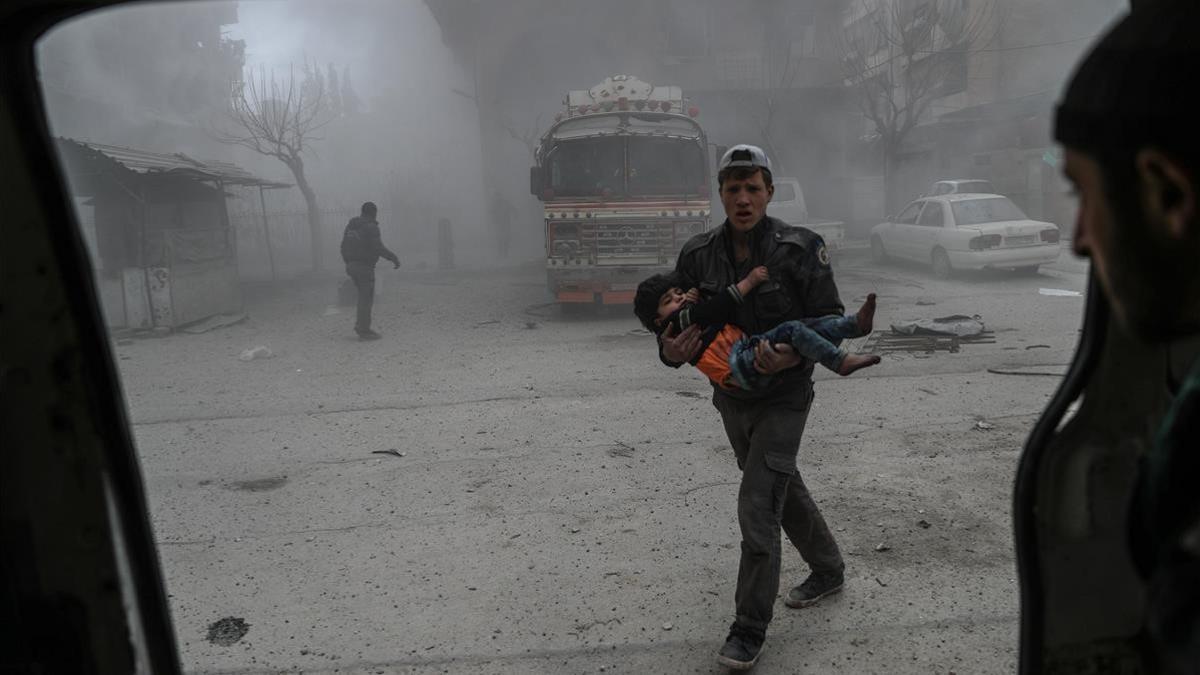 Un voluntario de los Cascos Blancos sirios lleva a un niño herido en brazos hasta una ambulancia, tras un bombardeo en Duma (Guta Oriental), el 22 de febrero.
