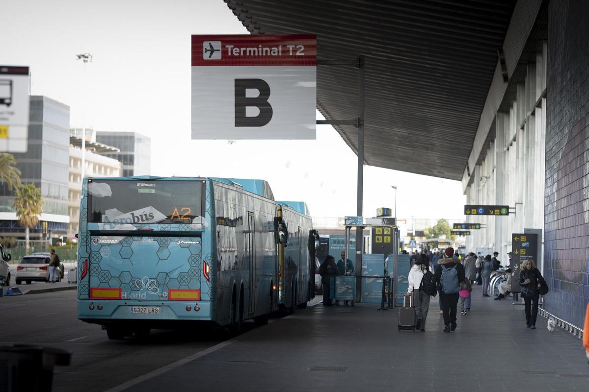 Varios pasajeros descienden de un bus en la entrada de la terminal T2 del aeropuerto de Barcelona-El Prat.