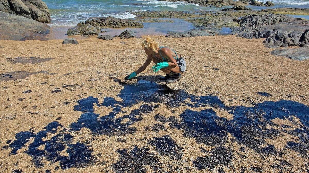 Una voluntaria recoge restos de crudo en la arena de una playa cerca del centro turístico de Oporto de Busca Vida en Lauro de Freitas, estado de Bahía.