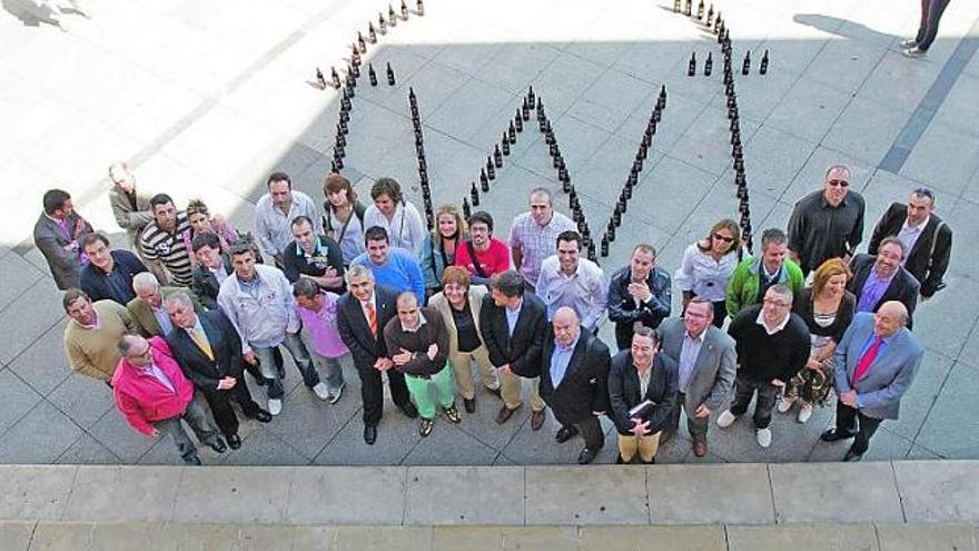 Hosteleros, políticos y organizadores del «Famouos Wine Festival», ayer, en la plaza de España, con el logo del certamen dibujado con botellas de vino.