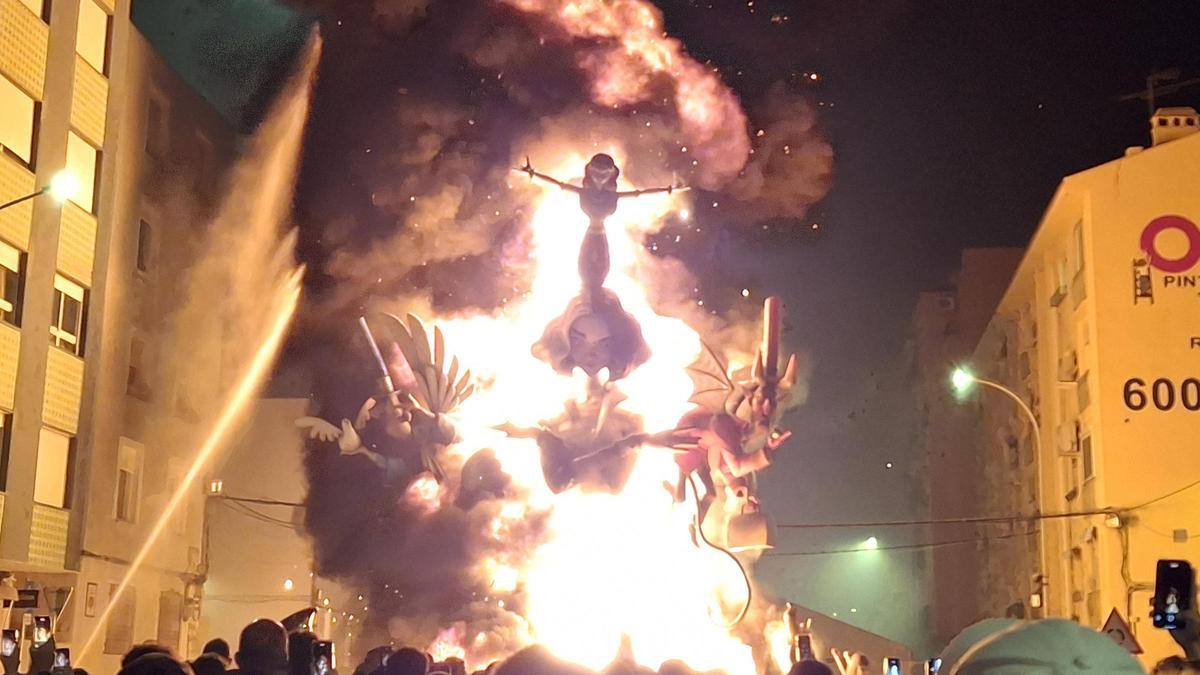 La cremà de una de las fallas de Dénia; a la izquierda, los chorros lanzados por los bomberos para controlar las llamas