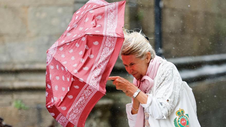 Una mujer se protege del viento y la lluvia en Santiago de Compostela. EFE/Lavandeira jr