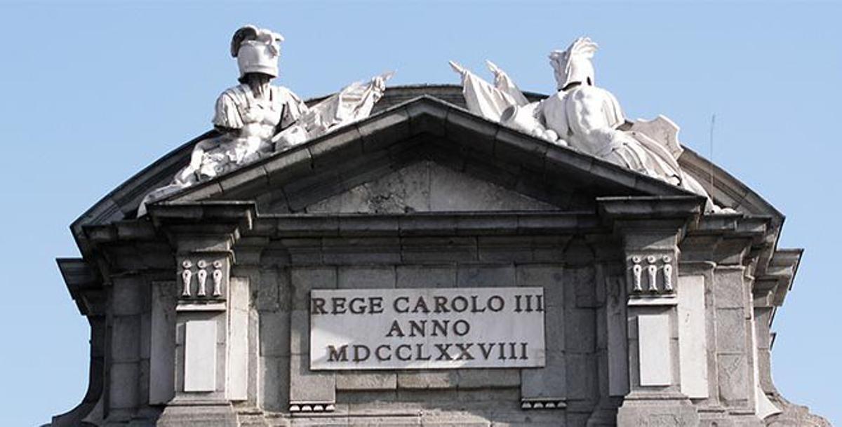 El friso y la cornisa de la Puerta de Alcalá en la Plaza de la Independencia de Madrid, decorados con estatuas neoclásicas y un letrero grabado con el nombre del rey Carlos III y el año de construcción