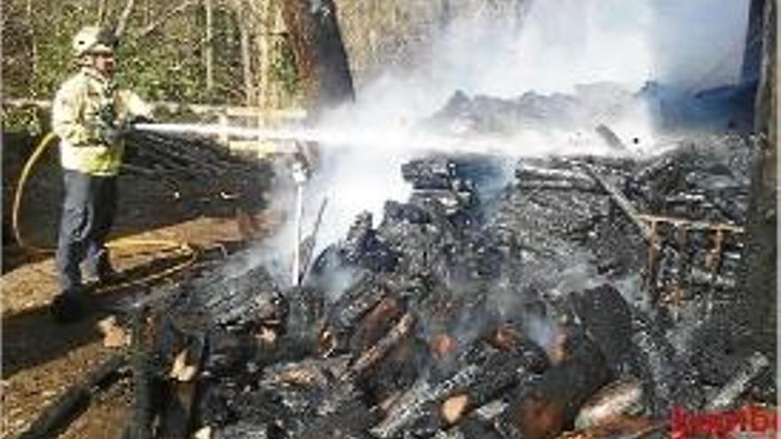 Els efectius del Bombers apagant la fusta del cobert de Santa Pau.