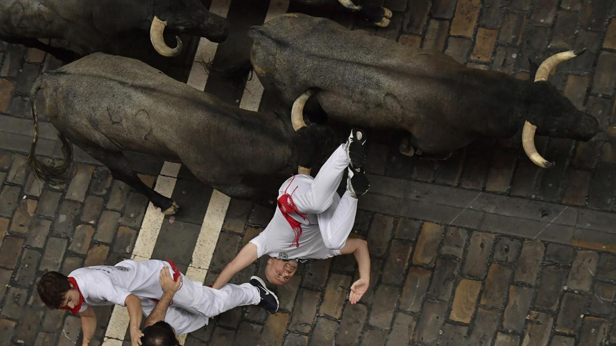 Dos mozos tropiezan perseguidos por toros de la ganadería José Escolar, en el segundo encierro de San Fermín.