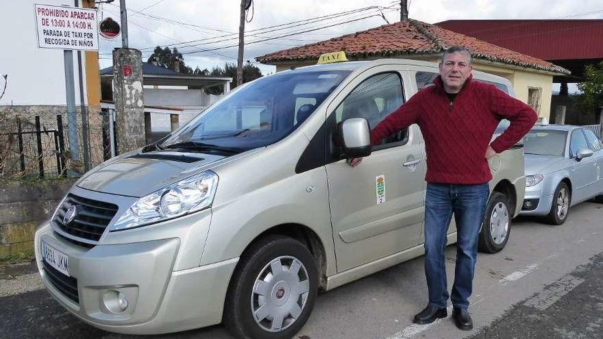 Eduardo López, con su taxi ante la escuela infantil de Ois en Coirós, esperando a trasladar a dos niños.