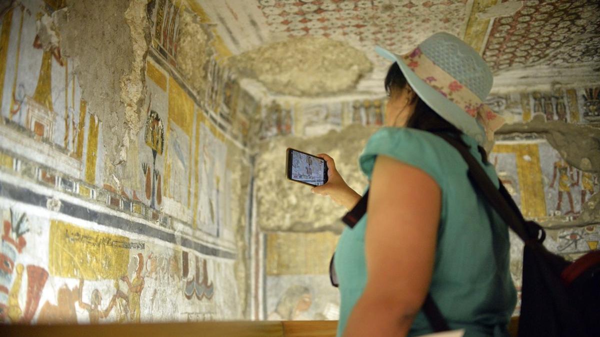 Una mujer fotografía el interior de una de las tumbas restauradas en Dra Abu al Naga, en Luxor.