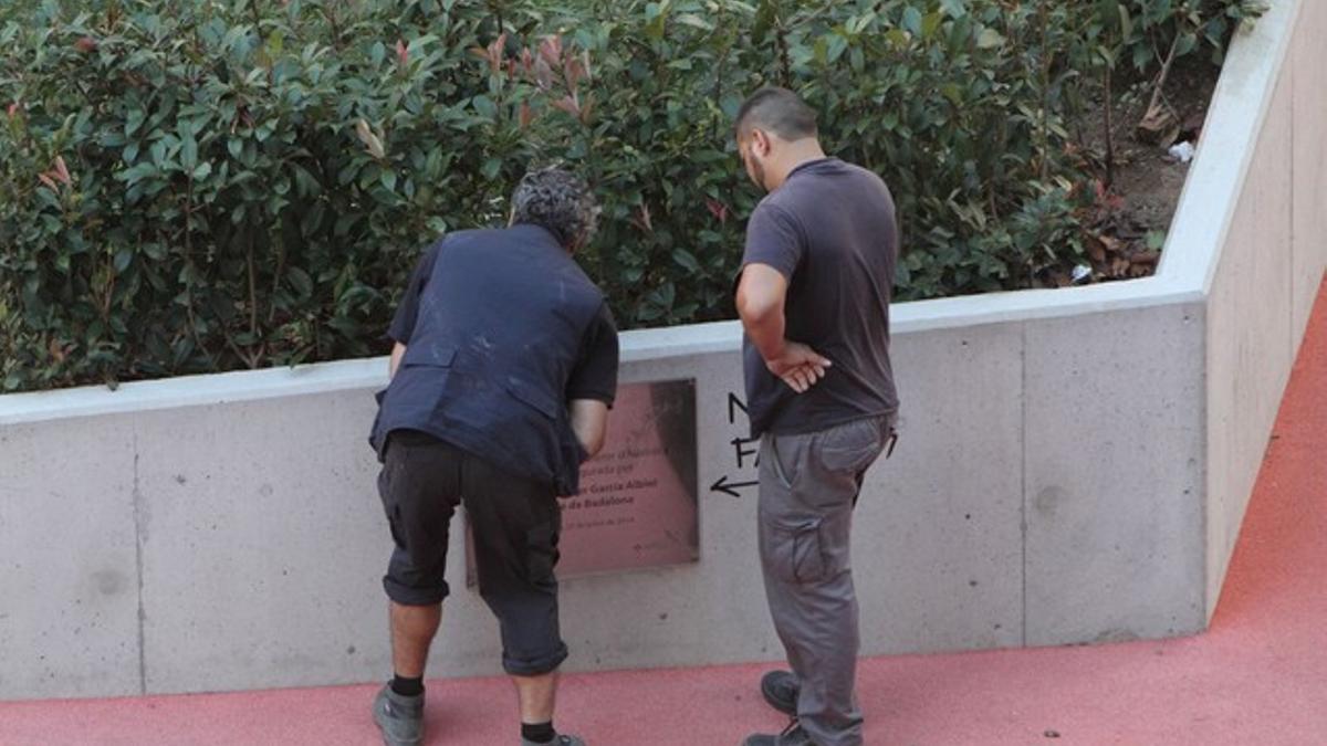 Operarios de la brigada municipal de Badalona retirando el rótulo que recordaba la inauguración de las escaleras mecánicas del barrio de Sant Crist por parte de Xavier García Albiol.