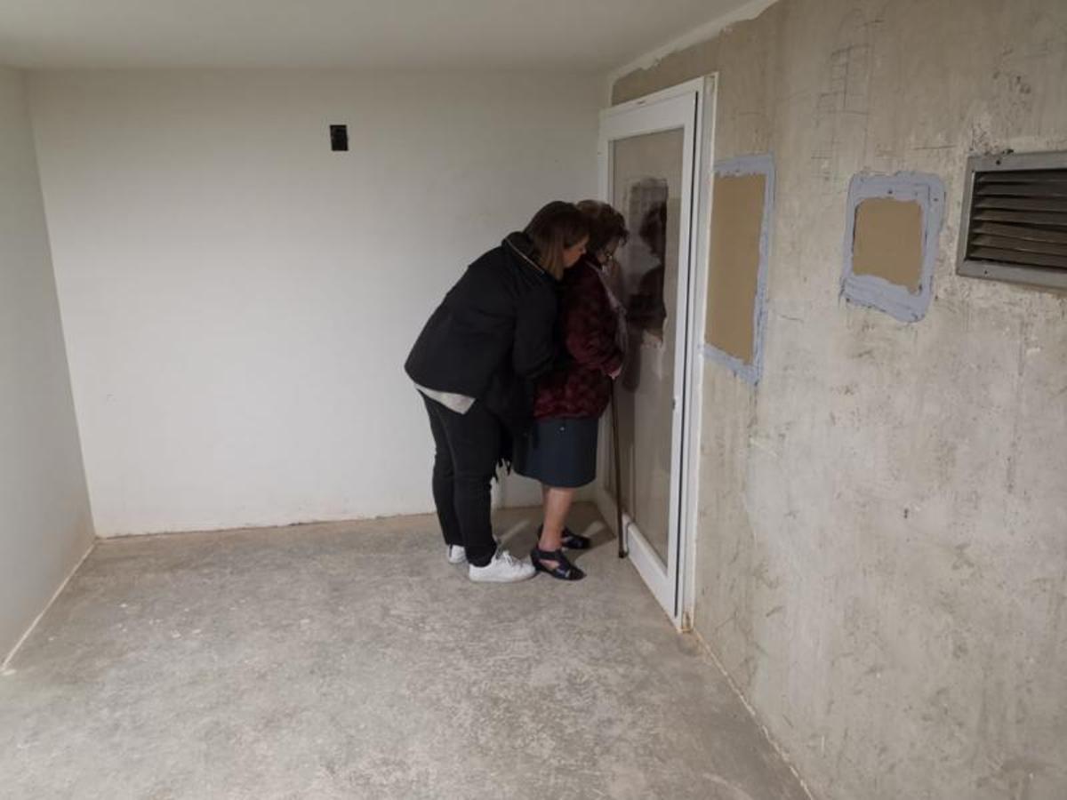 Dos familiares de enterrados en el Valle de los Caídos se asoman a un agujero en la pared de una cripta intentando ver las cajas de sus parientes en marzo de 2018.