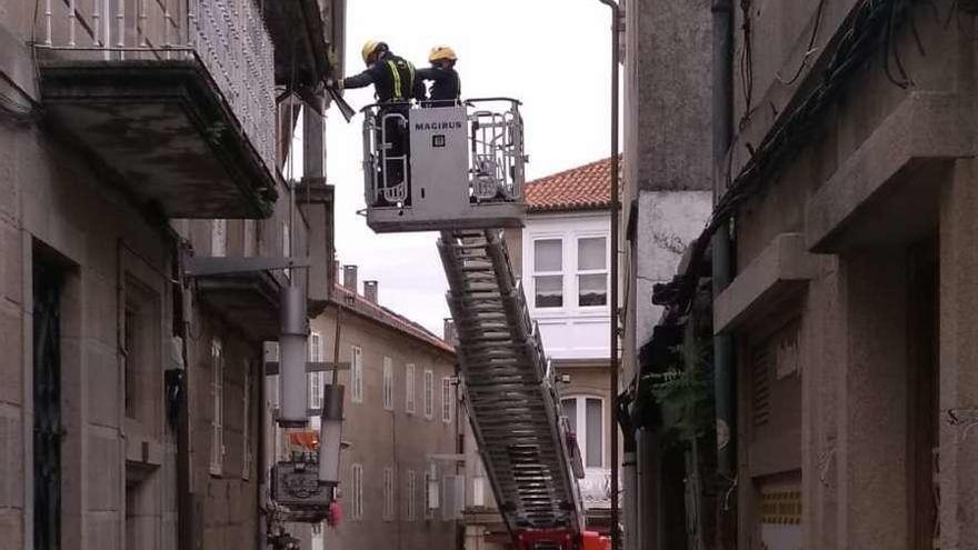 Agentes de Bomberos retiran el canalón de la vivienda de la calle Palma. // FdV