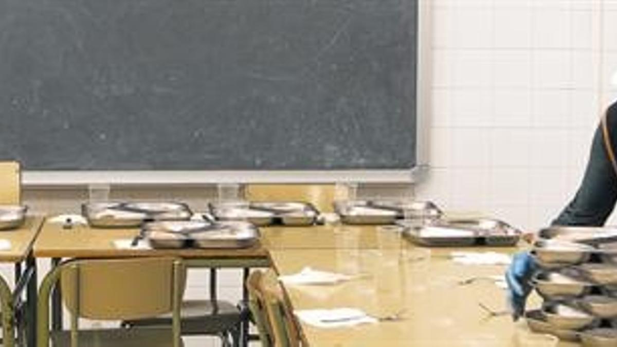 Una monitora coloca las bandejas de comida en el comedor escolar del colegio Josep Boada,en Badalona, a finales del curso pasado.