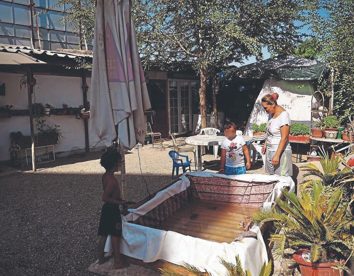 Cristina y sus hijos en una piscina improvisada con madera y una lona.