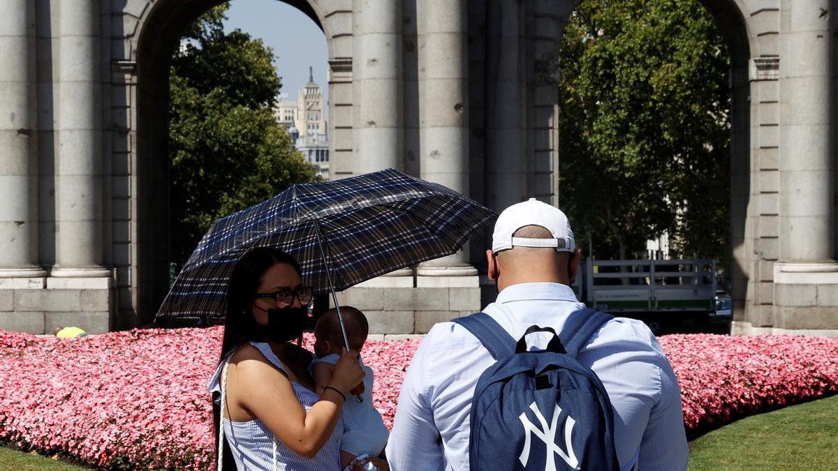 Una pareja de turistas, este lunes ante la Puerta de Alcalá en Madrid.