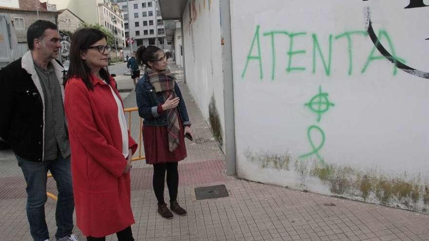 Carme da Silva, junto a Demetrio Gómez y Anabel Gulías, observan las pintadas ante su domicilio. // S. A.