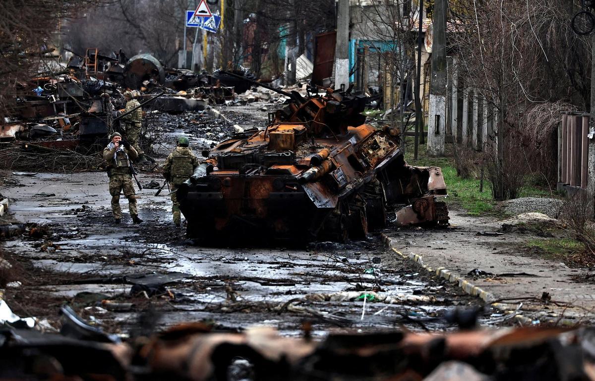 A soldier takes a photograph of his comrade as he poses beside a destroyed Russian tank and armoured vehicles, amid Russias invasion on Ukraine in Bucha, in Kyiv region