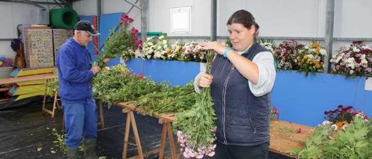 Mari Carmen Menéndez y Gloria García limpian una tumba en el cementerio de Tineo, a la que este año han tenido que retirar los centímetros de nieve que se acumulaban sobre ella.