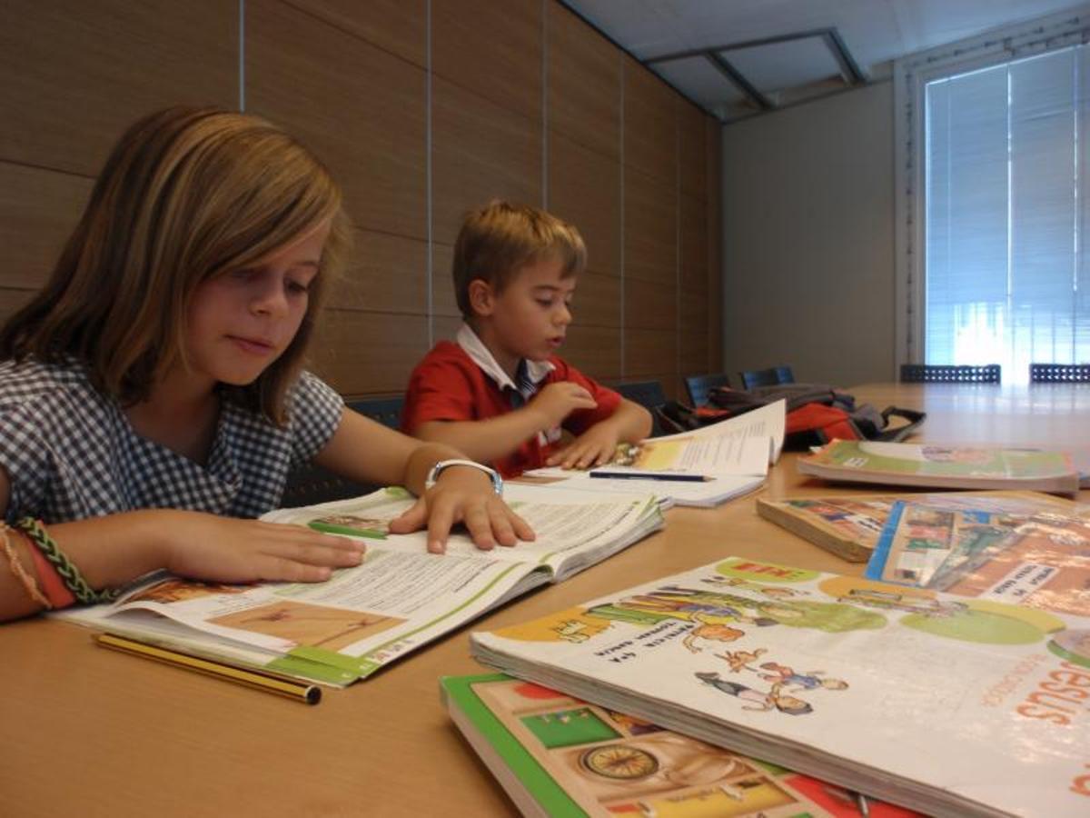 Una xiqueta i un xiquet llegint en classe