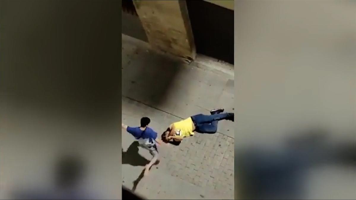 Un hombre da patadas en la cabeza a otro mientras yace en el suelo