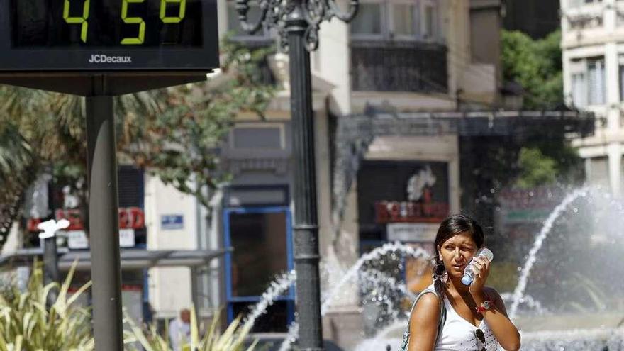 Una joven junto a un termómetro que marca 45 grados.