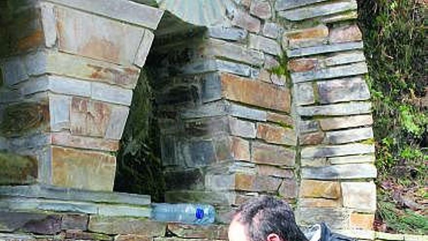 Un tapiego recoge agua en la fuente de la Virgen.