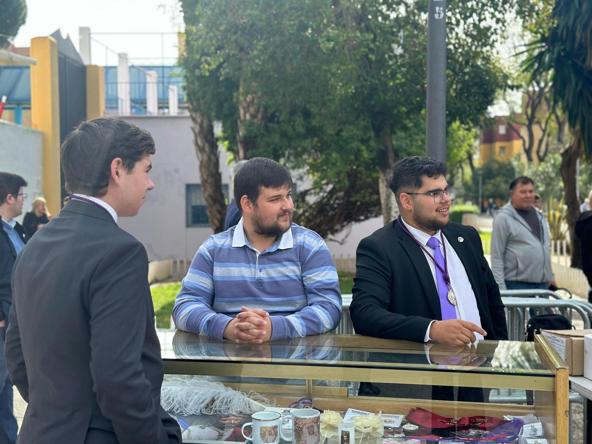 Un grupo de hermanos vende merchandising de la Hermandad de Pino Montano para recaudar fondos para la bolsa de Caridad de la Hermandad.