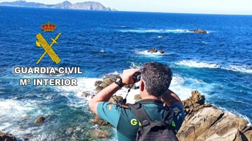 Un agente de la Guardia Civil rastrea el horizonte desde tierra.