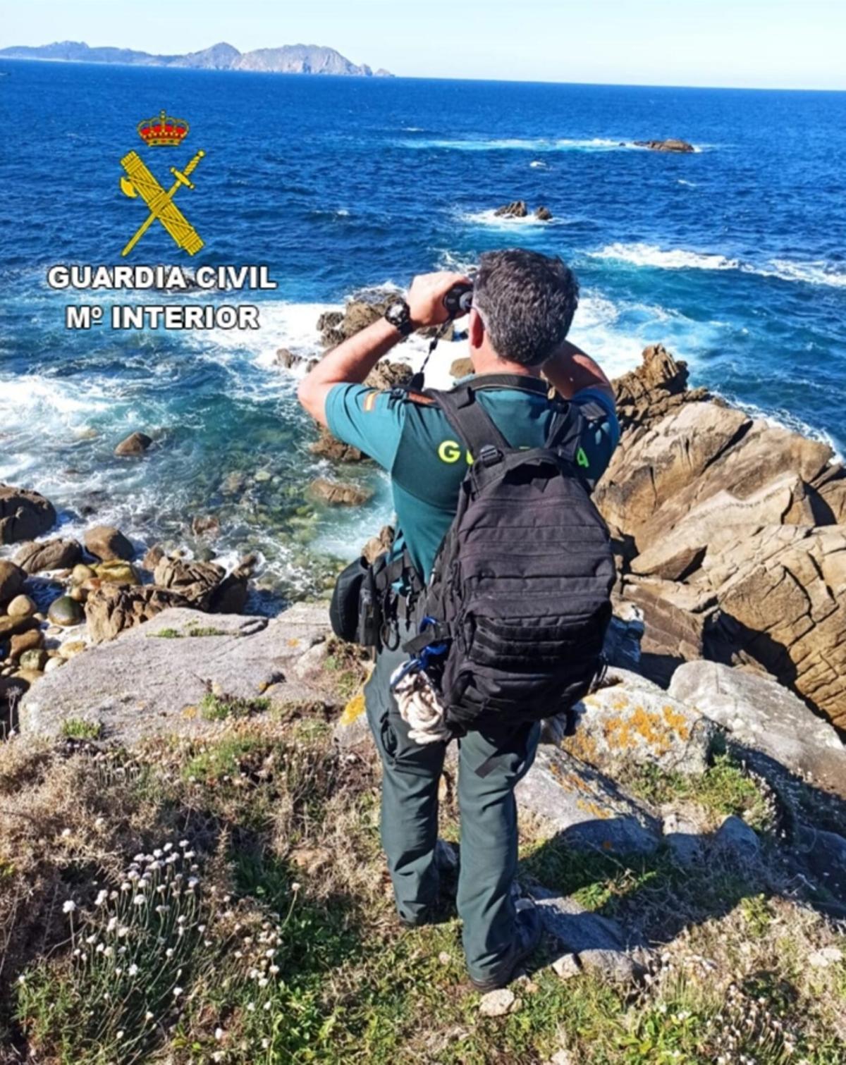 Un agente de la Guardia Civil rastrea el horizonte desde tierra.