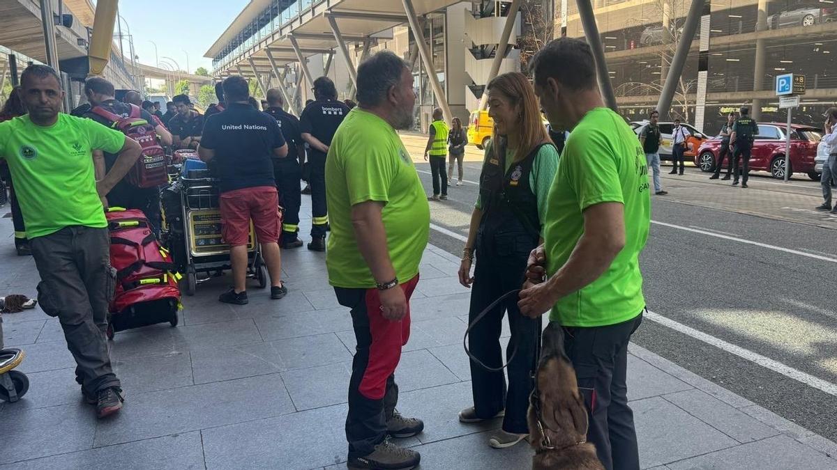 Con camiseta amarilla, Miguel de Prado, Wenceslao Fernández y Rubén Rocandio (este con la perra Kenia), hablan con la directora general de Protección Civil, Virginia Barcones, en el Aeropuerto de Barajas.