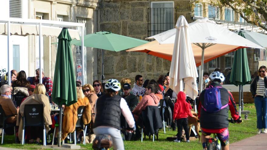 Una vista de personas disfrutando de una terraza de hostelería y del paseo marítimo de Cangas. |   // S.Á.