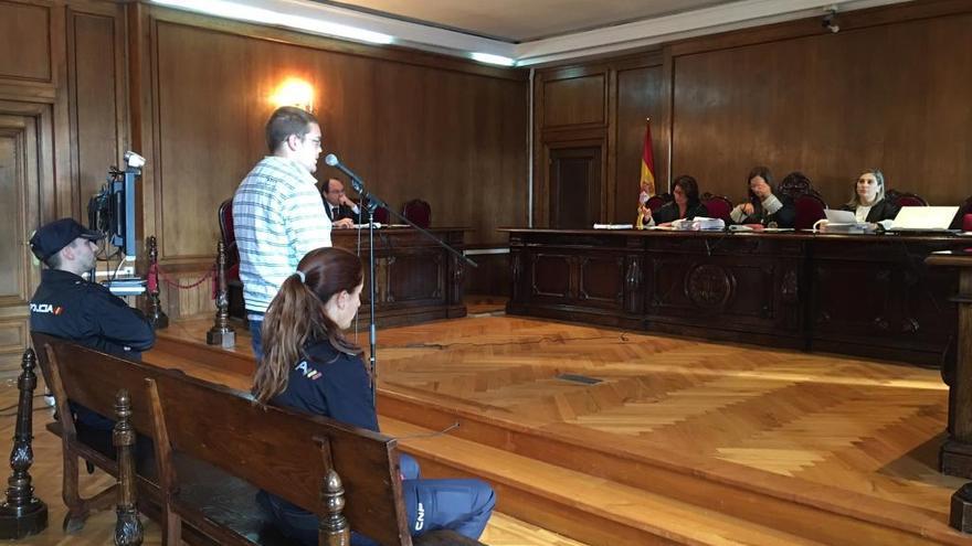 El acusado, custodiado por los dos policías nacionales, durante el juicio de hoy en la Audiencia de Pontevedra.