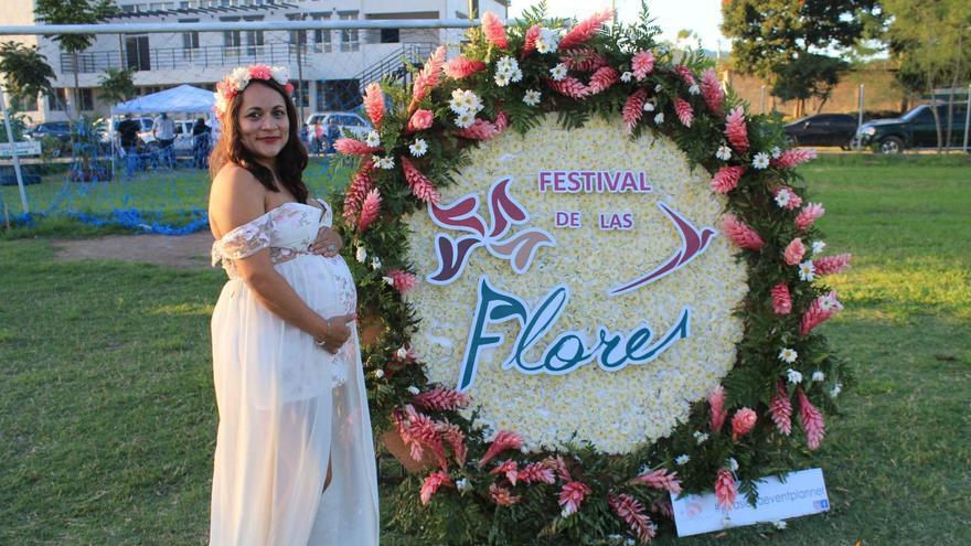 Una dona embarassada al costat d’una construcció floral en una imatge promocional del festival de les flors de Siguatepeque, molt semblant al de Girona.