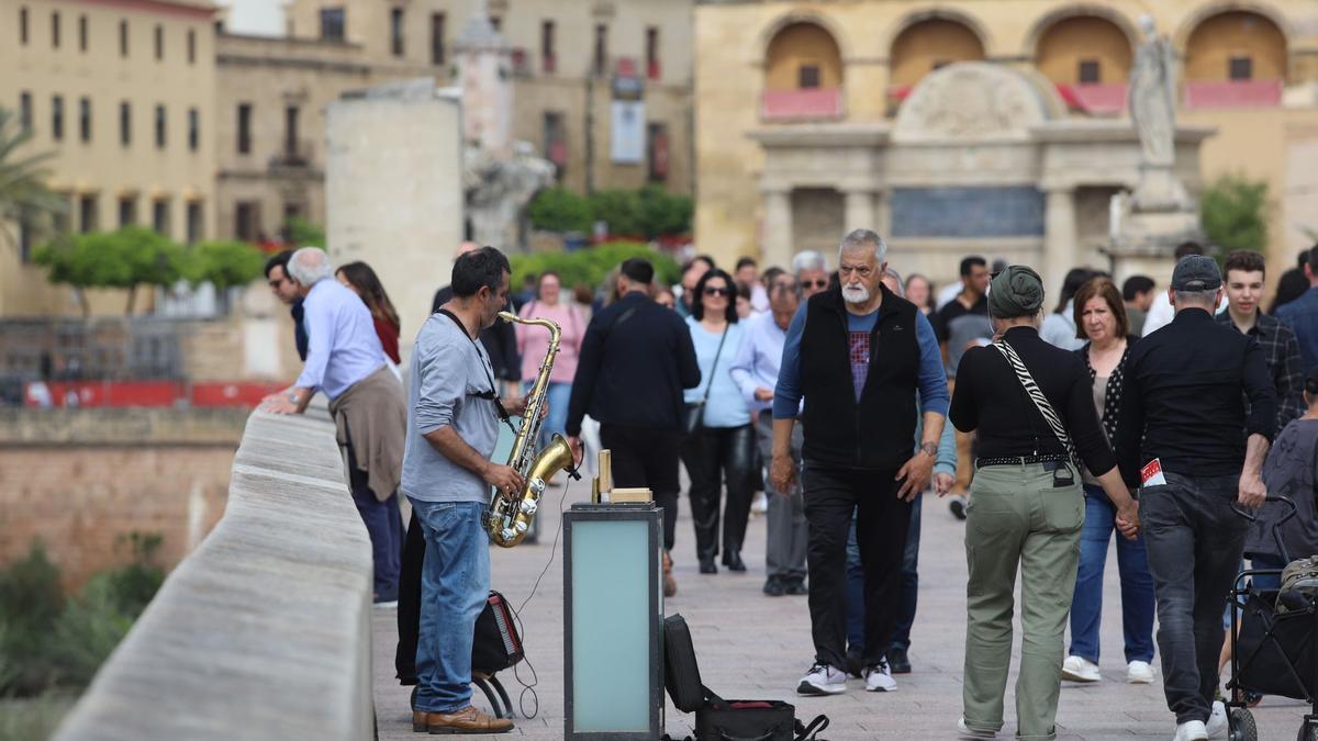 Varias personas caminan por el Puente Romano de Córdoba, este Domingo de Ramos.