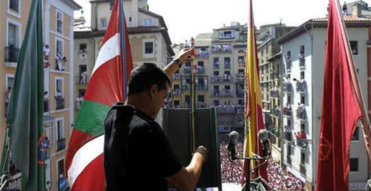 Un miembro de la pirotecnia valenciana de Caballer coloca el cohete en el balcón del Ayuntamiento de Pamplona.