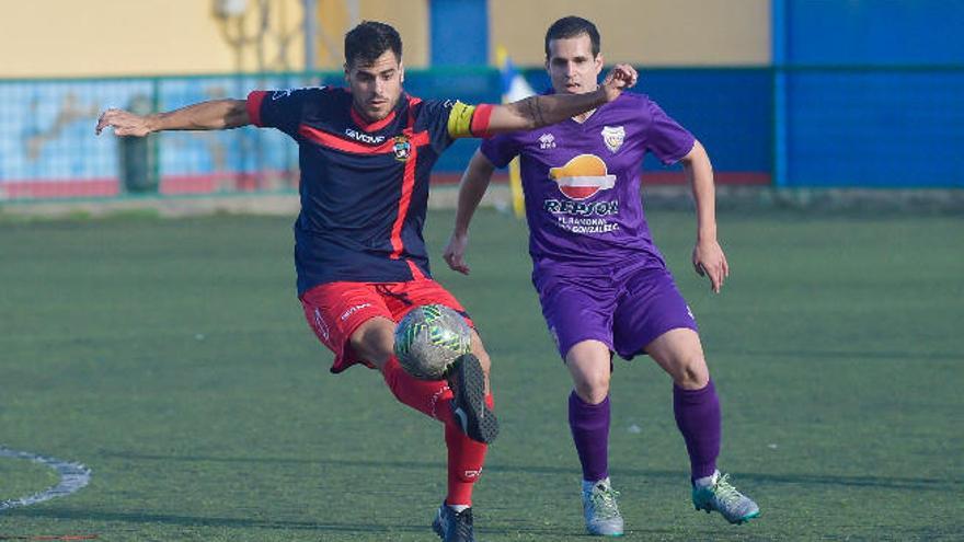 El capitán del Telde controla el balón ante un jugador rival.