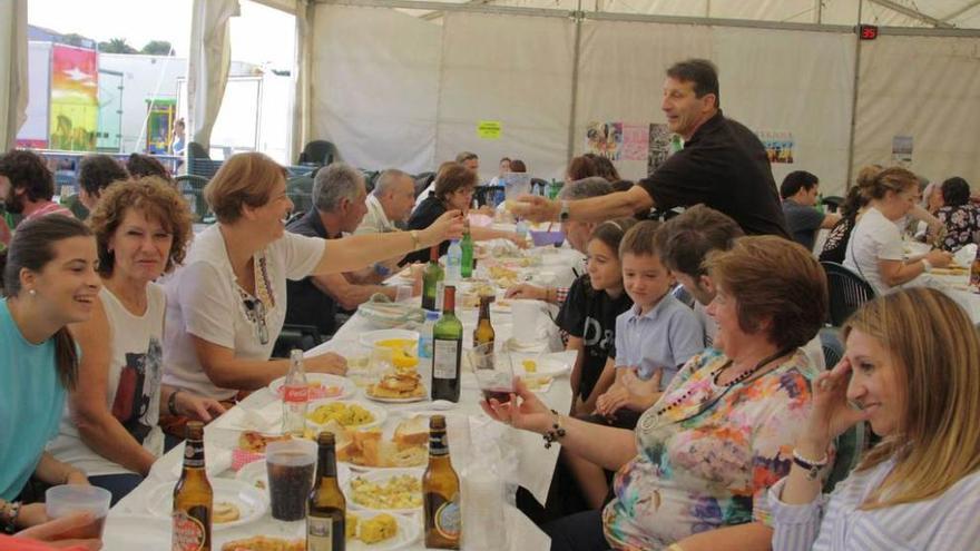 Comensales, ayer, en Guimarán mientras Abel Amado le entrega un culín de sidra a Pili Suárez.