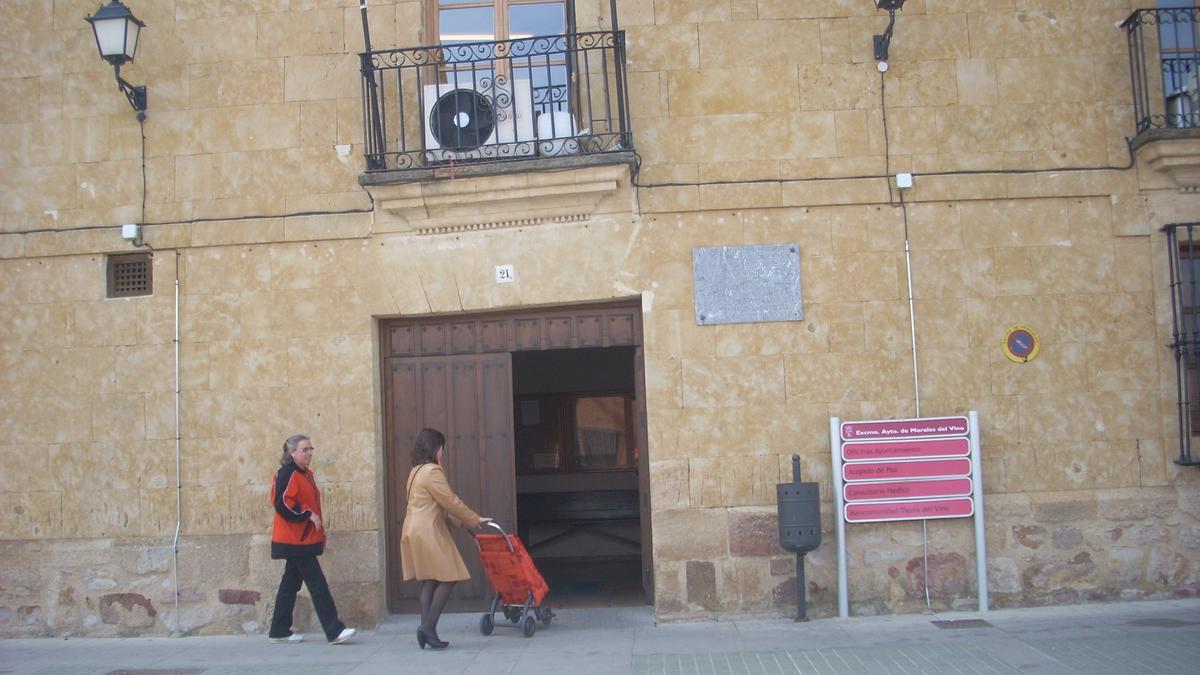 Dos personas ante la puerta del Ayuntamiento de Morales del Vino.