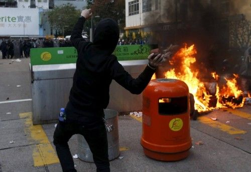A protester throws a stone towards riot police beside a fire set by protesters at Mongkok district in Hong Kong