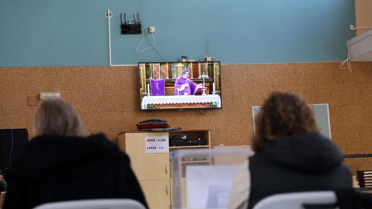 En el colegio electoral del centro cultural de Trabanca Badiña atienden a misa por televisión durante las votaciones