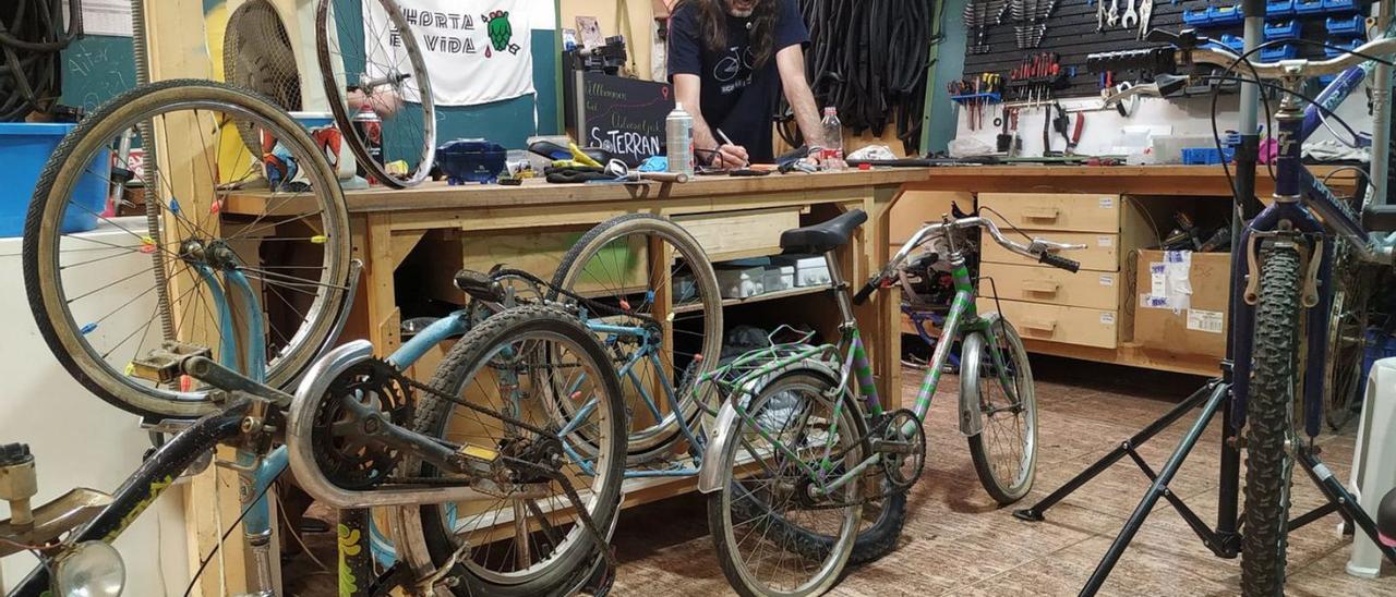 A la izquierda, taller de reparación de bicicletas de Soterranya, en el barrio Xenillet.  A la derecha, visita de Soterranya al grupo Aurora de Borriana. | C.S.