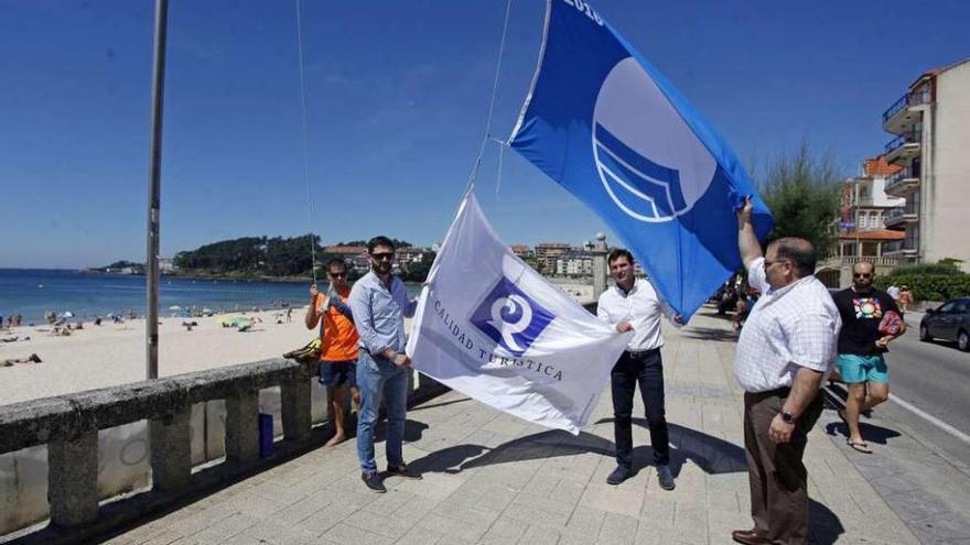 El alcalde, el concejal de Turismo y el presidente del CETS izan las banderas azul y de Q. // Gustavo Santos