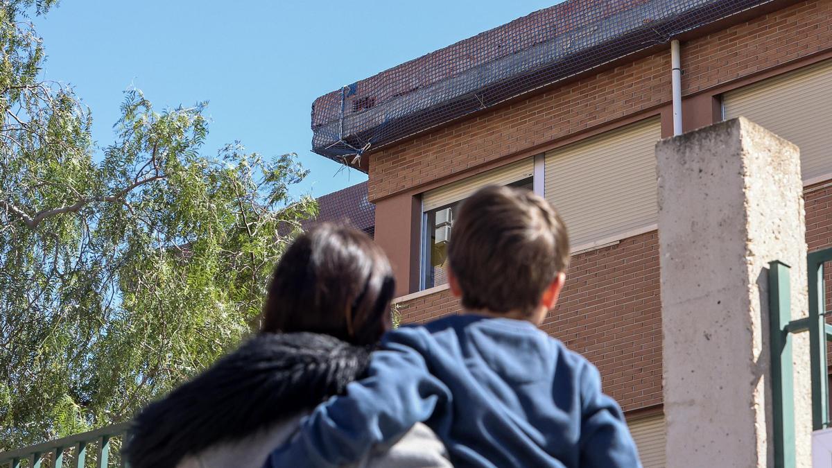 Una madre y su hijo miran a la cornisa desprendida en 2018 en el colegio Enric Valor de Alicante.