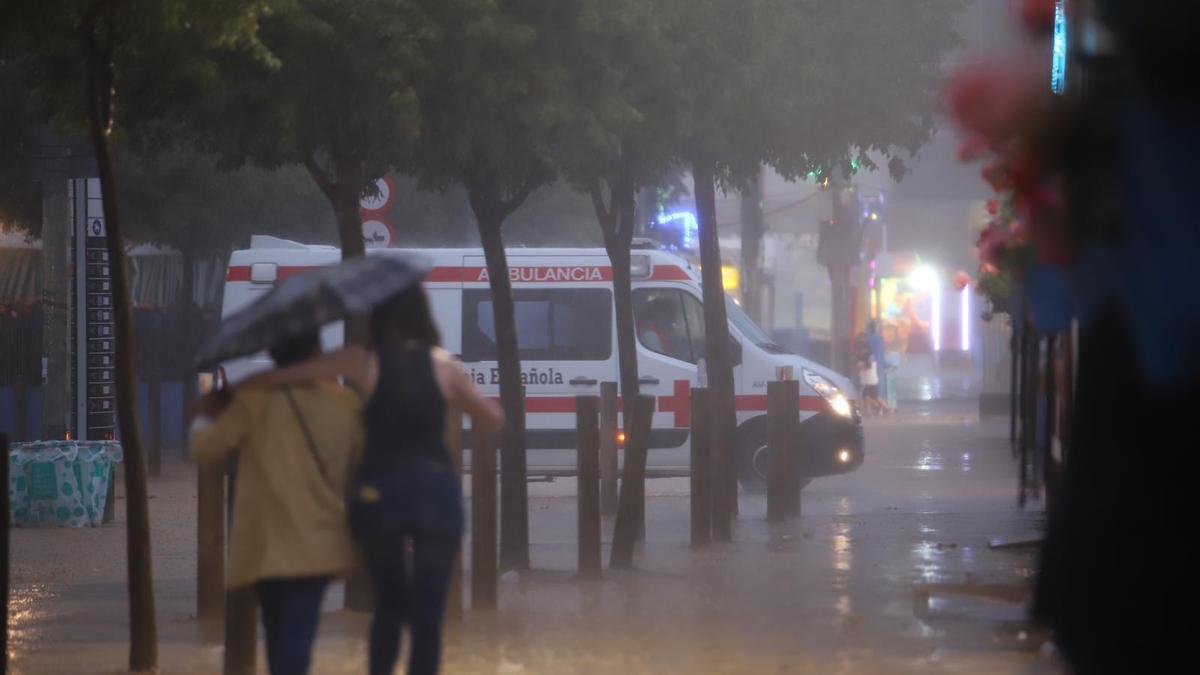 Una ambulancia entre la lluvia de la tormenta caída este martes por la tarde noche en la Feria de Córdoba.