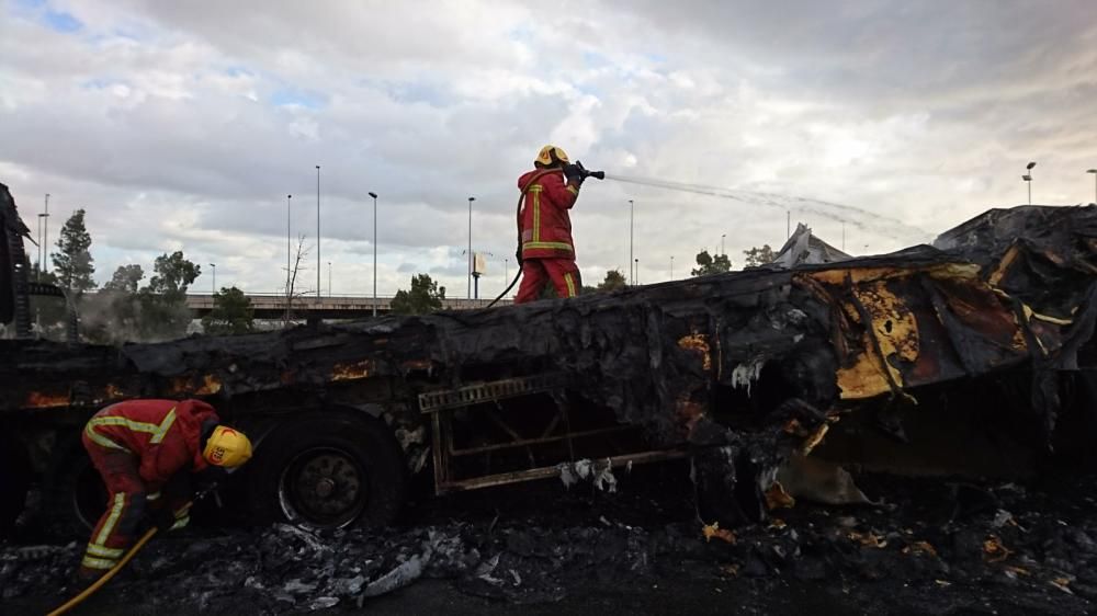 Los bomberos trabajan con el camión que ha ardido en la A-7, a la altura de Picassent.